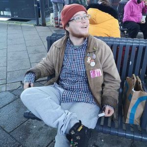 Picture of Rufus sitting on a bench wearing a beanie hat and jacket